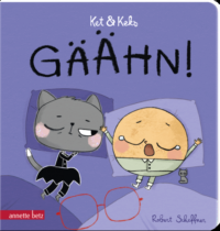 Eine Katze und ein Keks liegen im Bett, der Keks gähnt herzhaft.