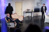 Drei Männer in festlicher Abendkleidung auf einer Theaterbühne