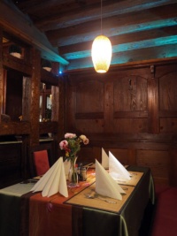 Ein Tisch in einem Resturant. Die Wände sind mit dunklem Holz verkleidet. Eine Deckenlampe beleuchtet den Tisch. 