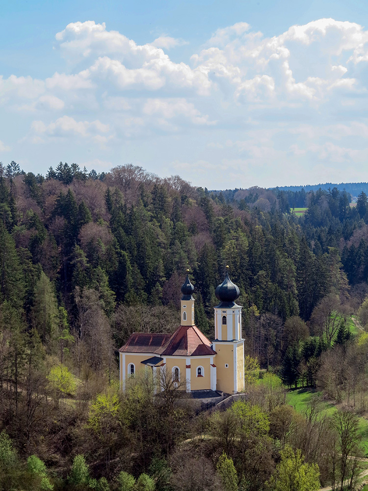Einen kleine Kapelle mit Zwiebelturm in einem dichten Wald