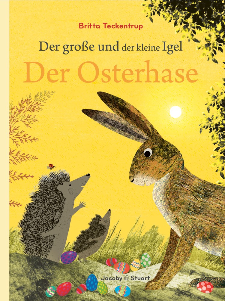 Im hone Gras einer Wiese treffen sich ein Hase und zwei Igel. zu ihren Füßen liegen viele bunte Ostereier.
