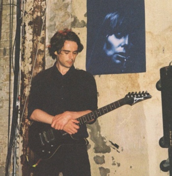 Ein Mann im dunklen Hemd, der eine E-Gitarre hält