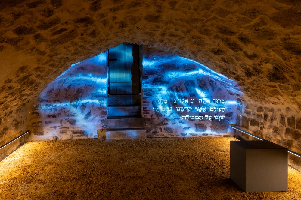 Ein nidriger Gewölberaum auf eine Wand wird ein SChriftzug projiziert