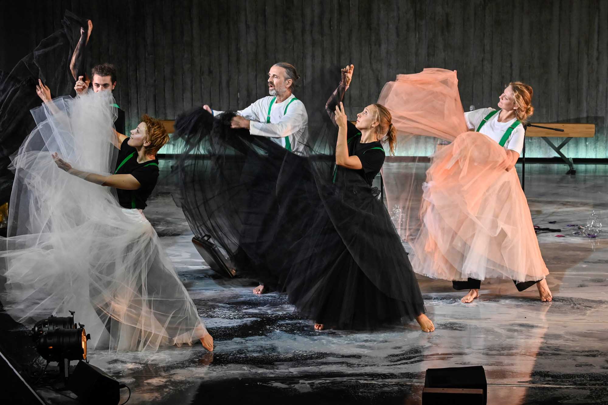 Schauspielerinnen in Kleidern tanzen auf einer dunklen Bühne