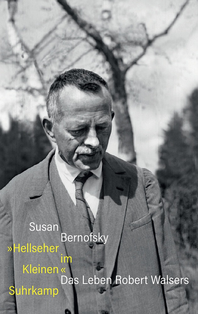 Ein Porträtfoto des Autors Robert Walser, der im Freien, im Sonnenschein, unter einem kahlen Baum steht.