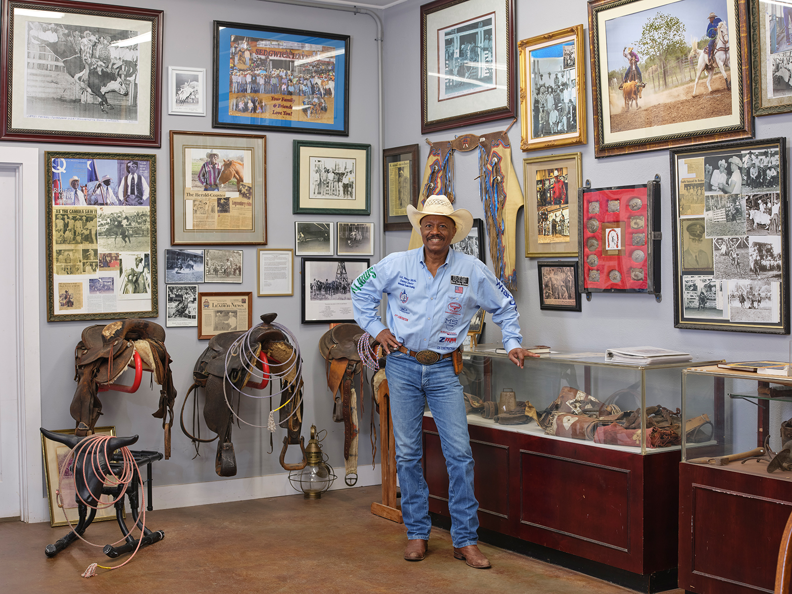 Ein Mann in Cowboy-Kleidung sthet in einem Museumsraum, in dem zahlreiche Cowboy-Devotionalien hängen.
